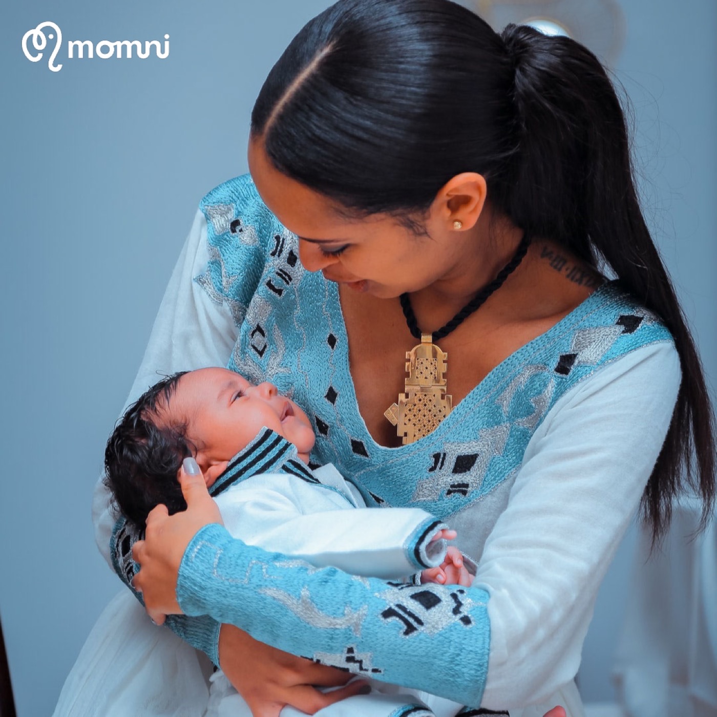 A Momni mama cradling her newborn close
